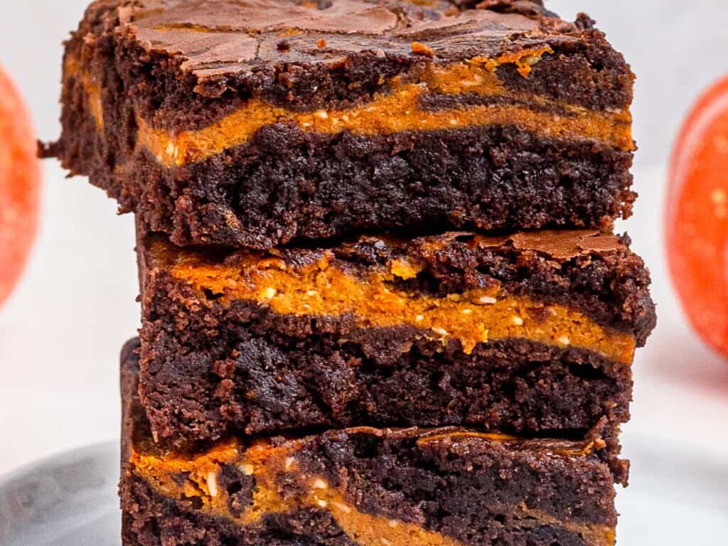 Brownies with pumpkin layer on a gray plate.
