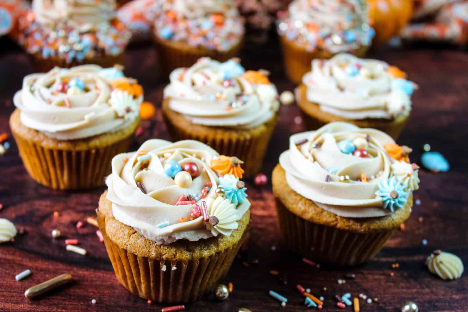 Pumpkin cupcakes with confetti sprinkles on top.