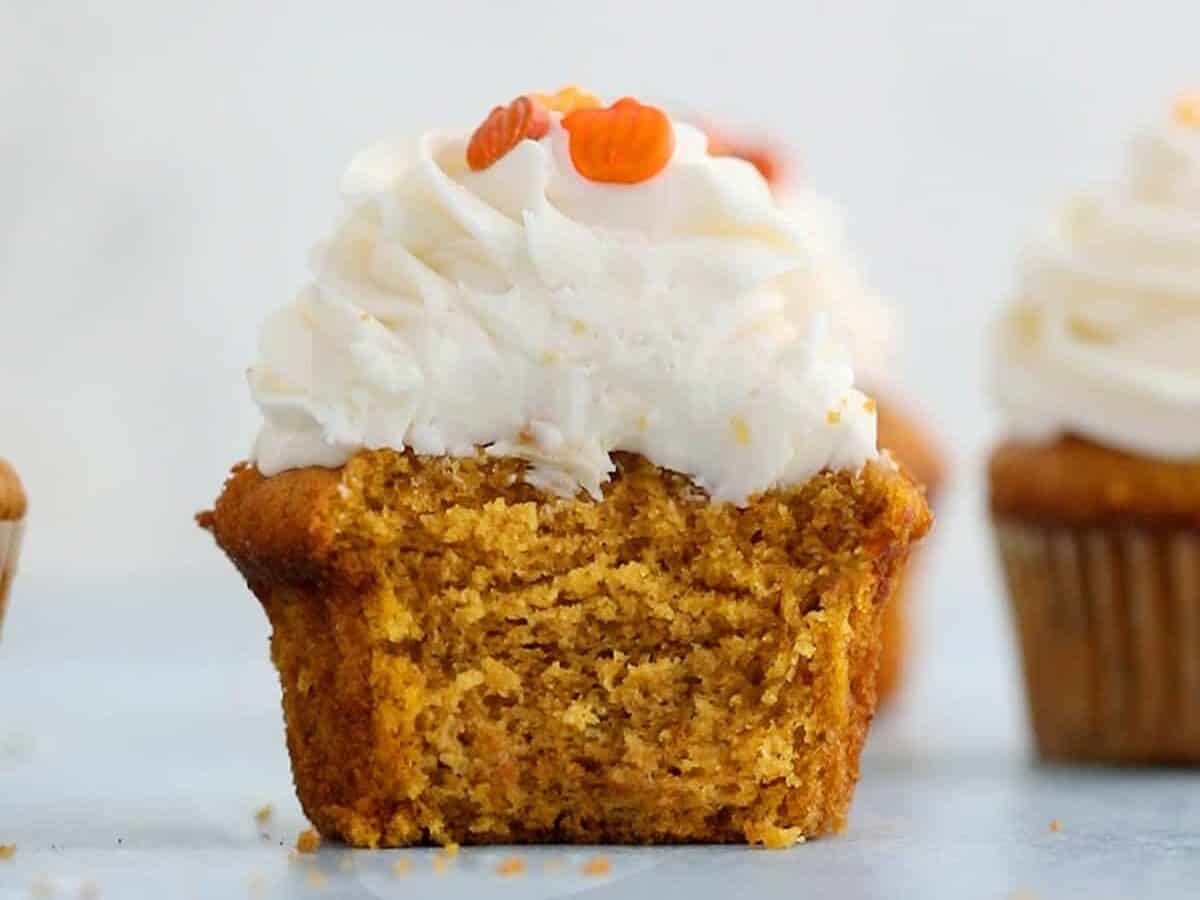 Pumpkin cupcake with tall frosting and bite out.