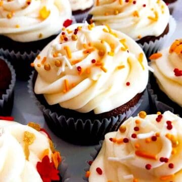 A group of fall-themed cupcakes with white frosting and orange sprinkles.