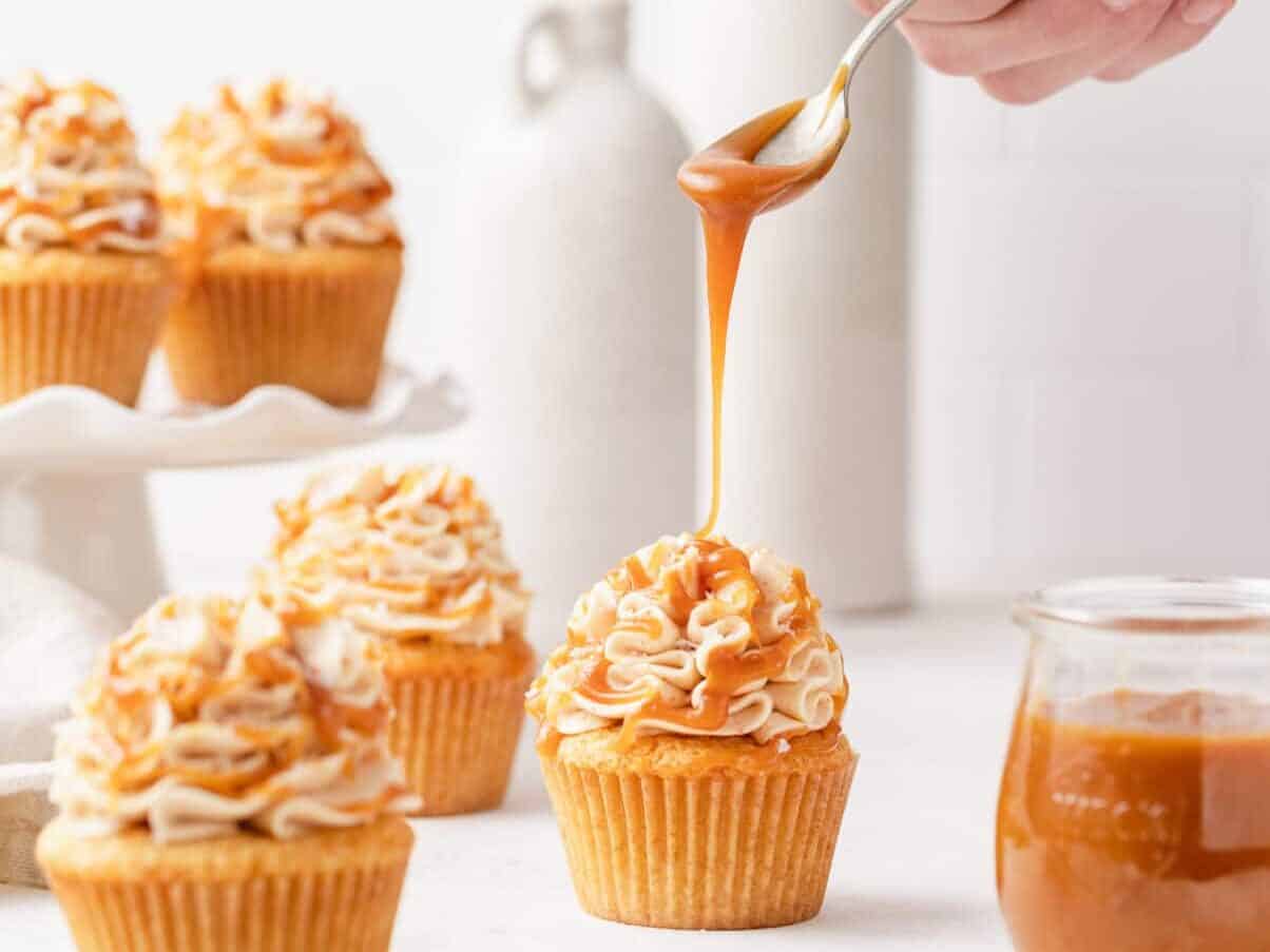 Brown butter cupcakes with caramel being dripped on top.