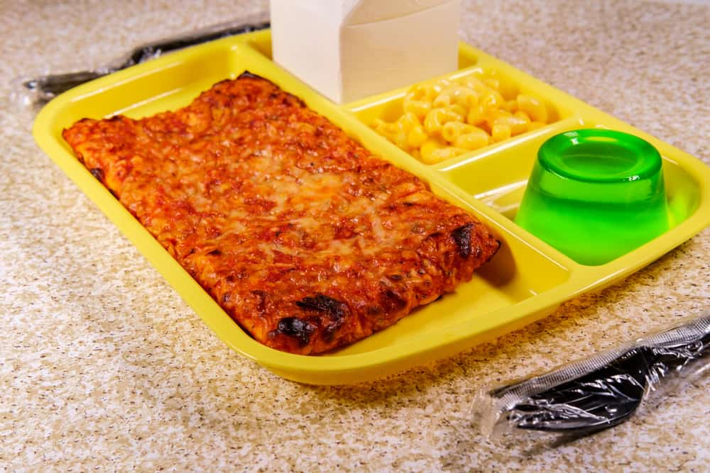 Grade school lunch tray with pizza with small carton of milk mac-n-cheese and green gelatin for dessert