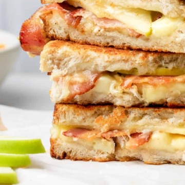 A stack of grilled sandwiches with apple slices and bacon, perfect for Fall.