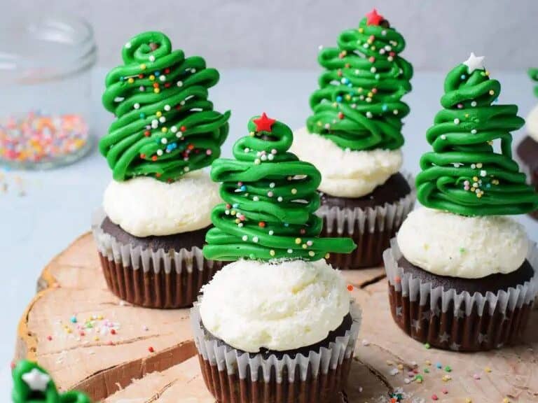 Christmas tree cupcakes on a wooden cutting board.