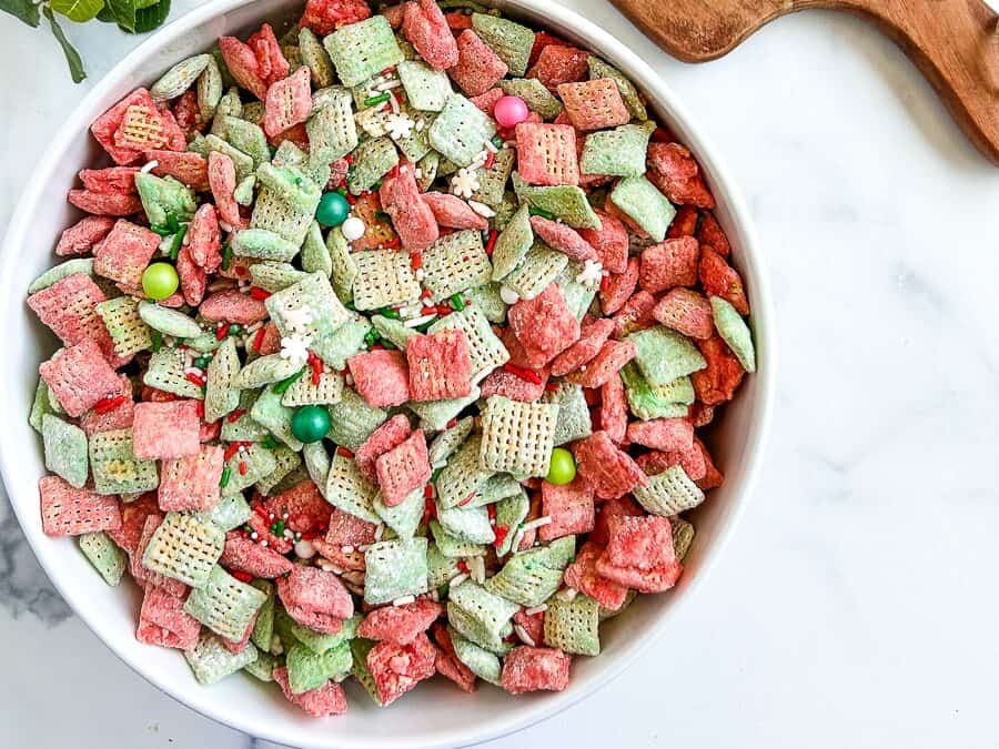 A white bowl filled with green and pink chex mix.