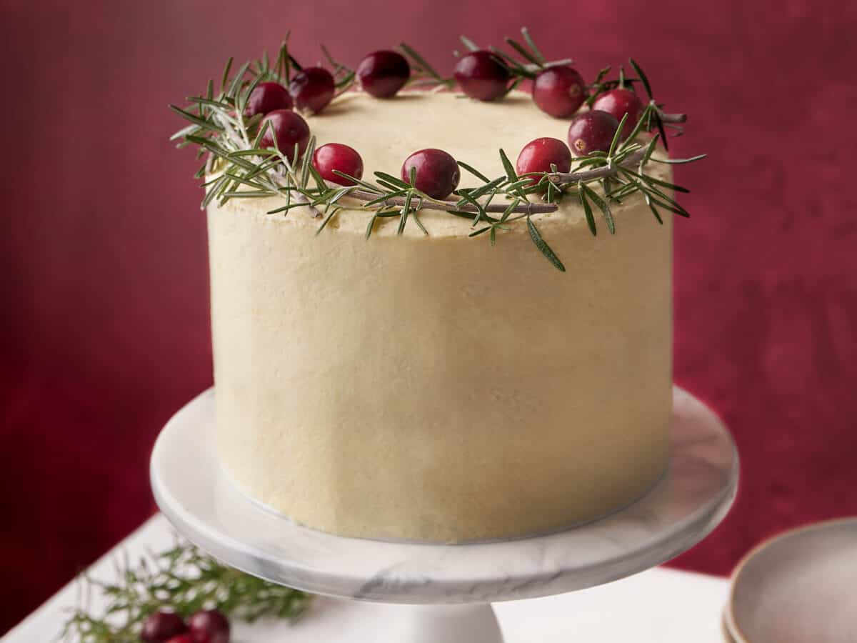A cake decorated with cranberries and sprigs of rosemary.