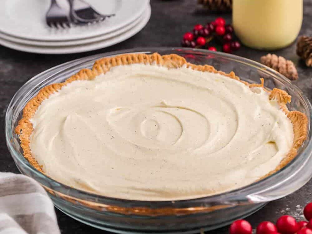 A pie in a glass dish with whipped cream and cranberries.