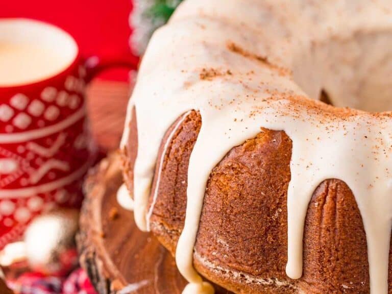 A bundt cake with icing and a cup of coffee.