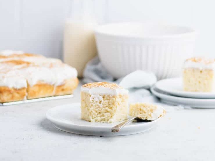 A slice of coconut cake on a plate with a fork.