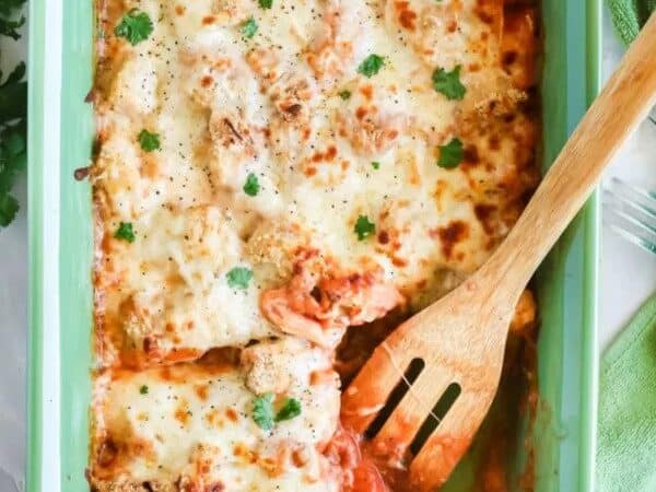 Chicken Parmesan Casserole on a dish with wooden spoon.