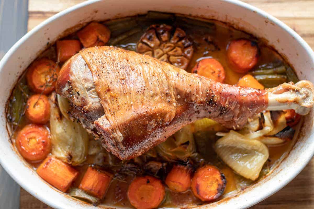 Perfect Roast Turkey Recipe with sauce and vegetables in an oval dish. 