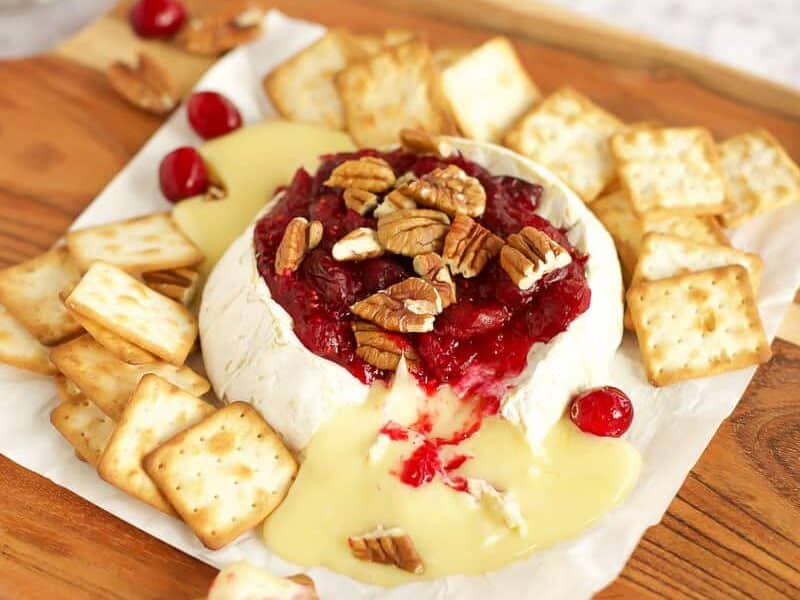 Baked Brie with Cranberry Sauce on a wooden chopping board.