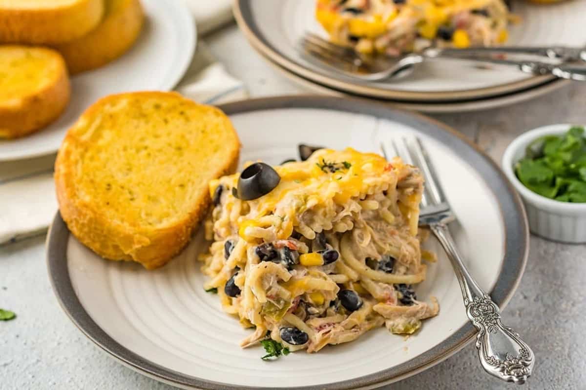 A serving of Fiesta Chicken Pasta Casserole Bake in a plate with bread.