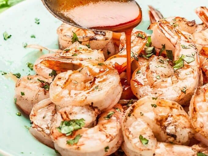 Grilled shrimp with sauce on a plate.