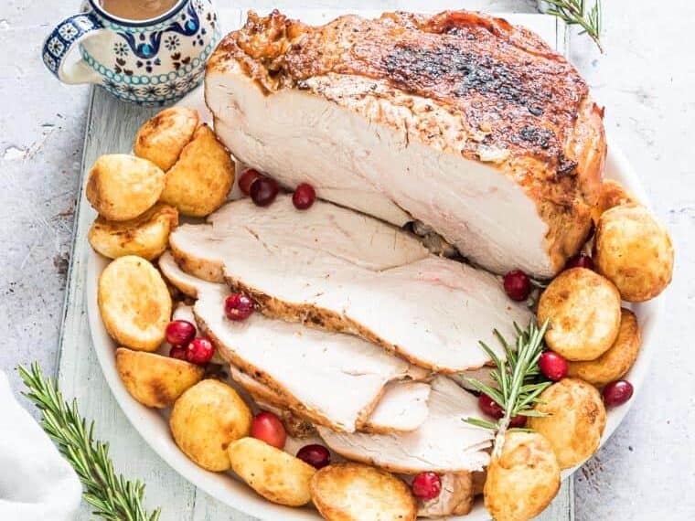 Air Fryer Turkey Breast served with potatoes, cranberries, and rosemary. 