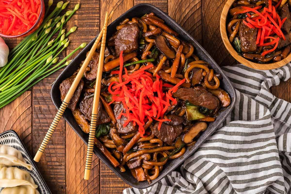 Beef and noodles stir fried with carrots and mushrooms.