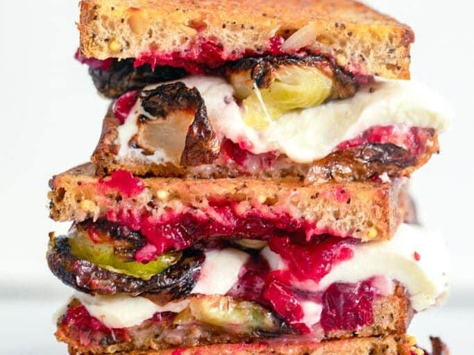 A stack of colorful grilled cheese sandwiches with brussels sprouts and cranberries.