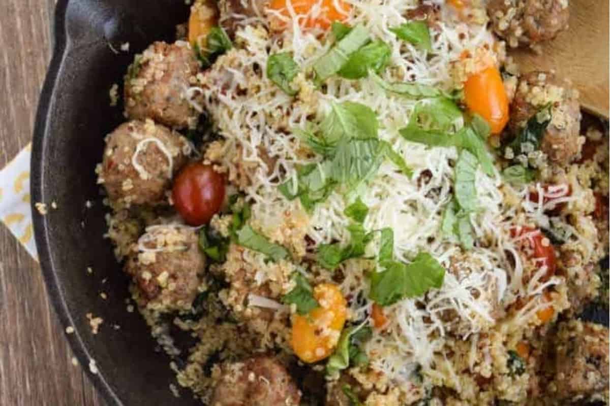 Cheesy quinoa with meatballs in a pan.