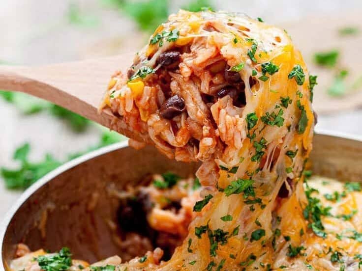 Chicken Enchilada Casserole scooped out using a wooden spoon. 