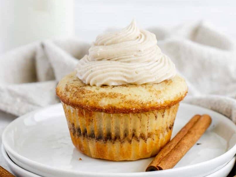 Cinnamon cupcakes with frosting and cinnamon sticks.