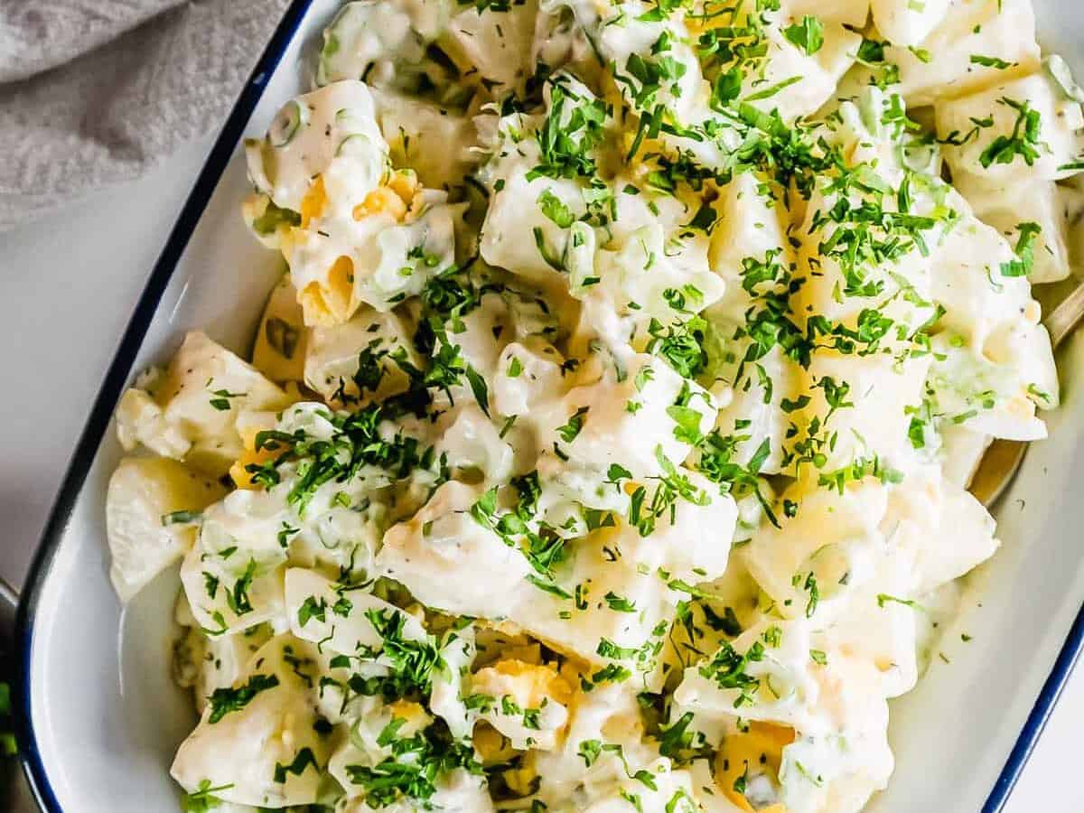 American potato salad in a bowl with green herbs.