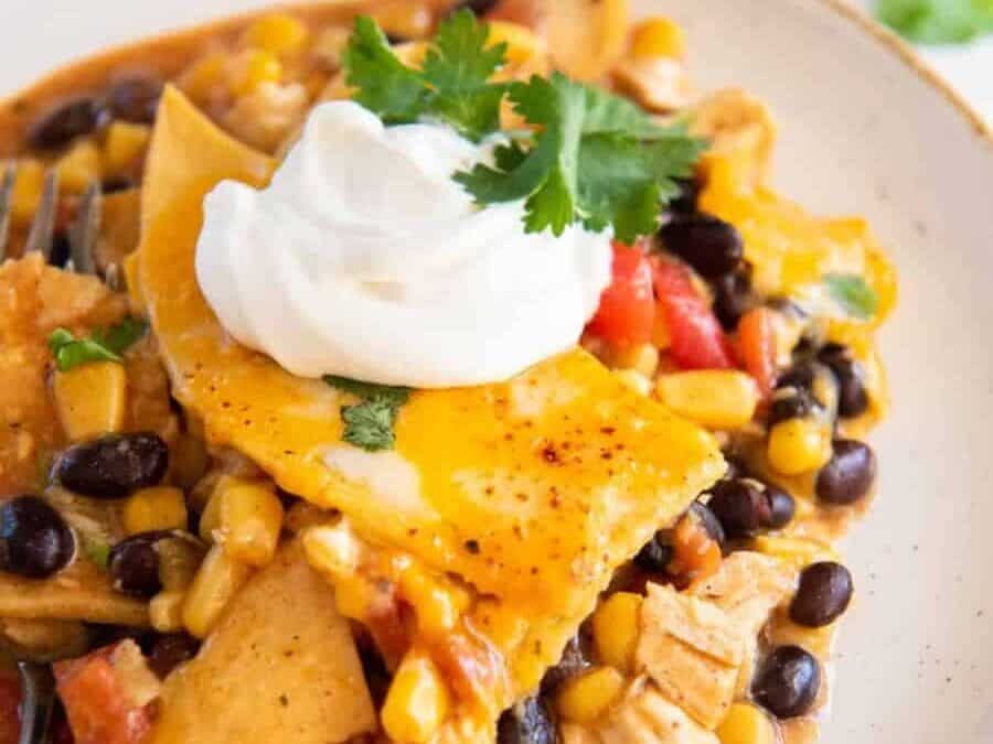 Black beans, corn and chicken in a casserole dish with a serving spoon.