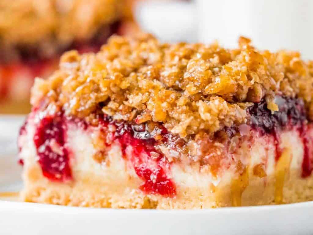 Cheesecake bars topped with cranberry and crumbs.