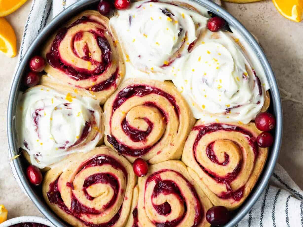 A pan of cranberry orange rolls with cream cheese frosting.