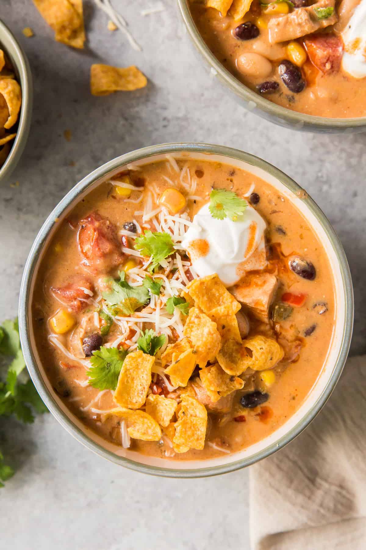 Creamy Southwest Chicken Soup topped with tortilla chips and cream.