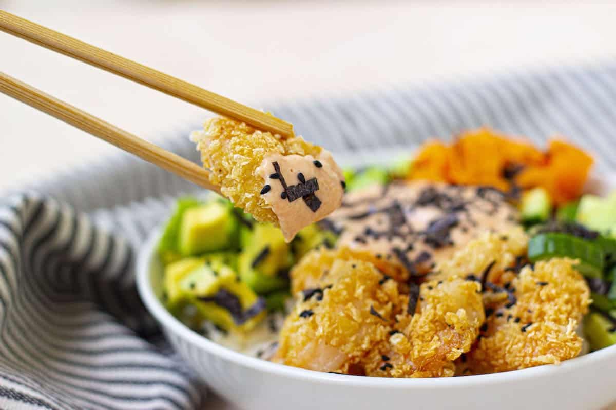 A bowl filled with chicken and vegetables with chopsticks.