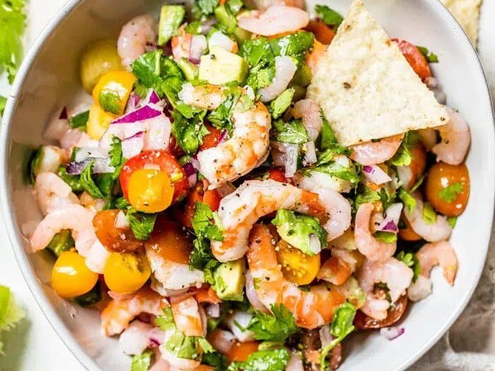 Shrimp salad in a white bowl with tortilla chips.