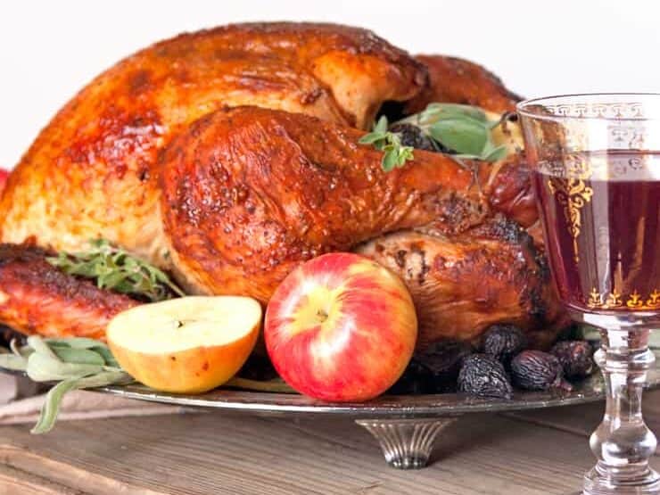 Fig-spiced whole turkey served on a dish with fruits. 