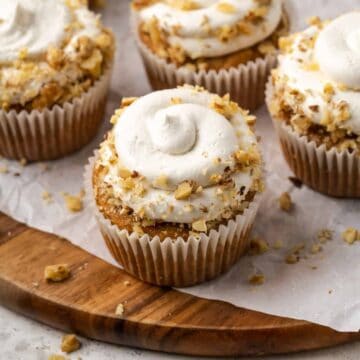Gluten free carrot cupcakes topped with whipped cream and walnuts.