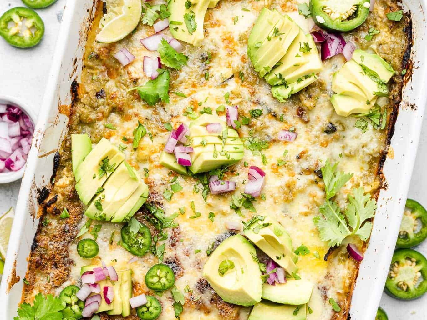 Chicken casserole topped with green chilies, avocado slices, and herbs.