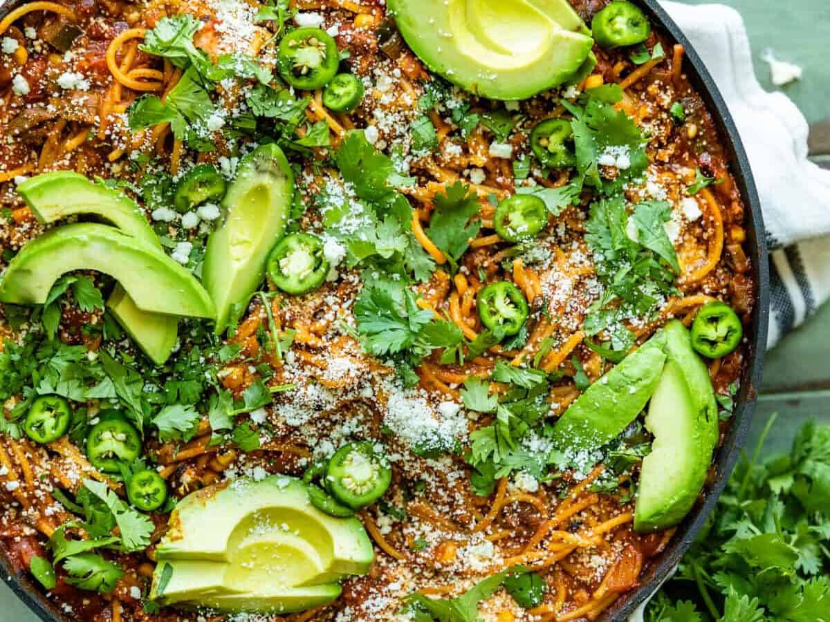 A skillet with spicy Mexican spaghetti topped with jalapenos.