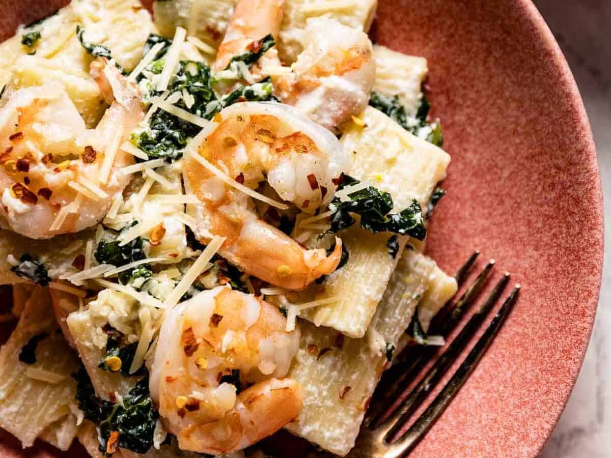 A plate of pasta with shrimp and kale.