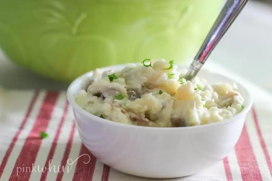 Bowl of mashed potatoes with herbs.