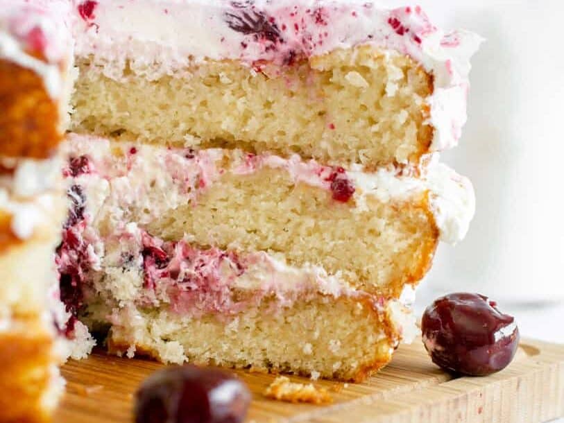 White forest cake sliced with cherries.