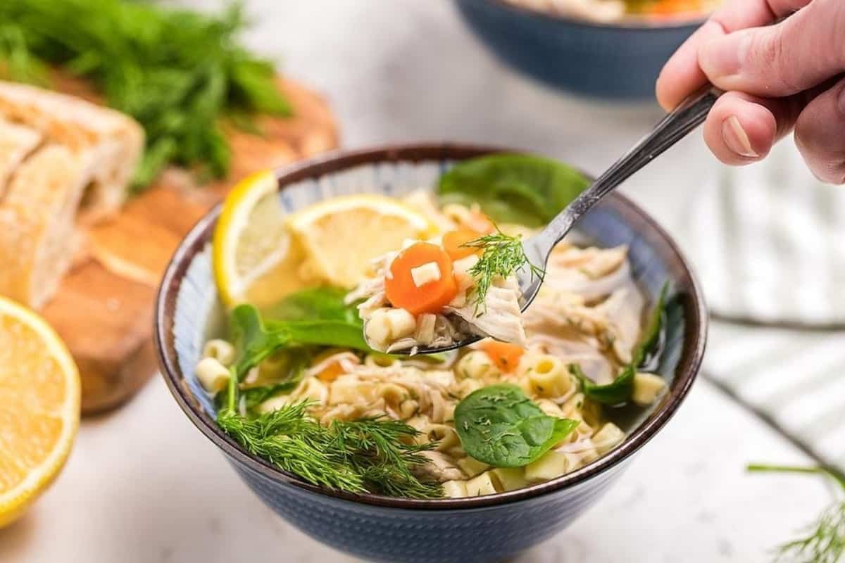 Greek lemon chicken soup with spinach leaves and chunks of carrots.