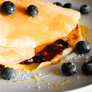 crepe with berries and syrup on a plate.
