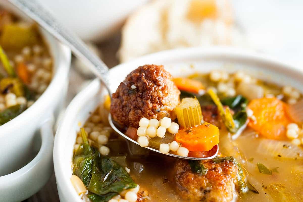 Italian wedding soup in a bowl with a spoon
