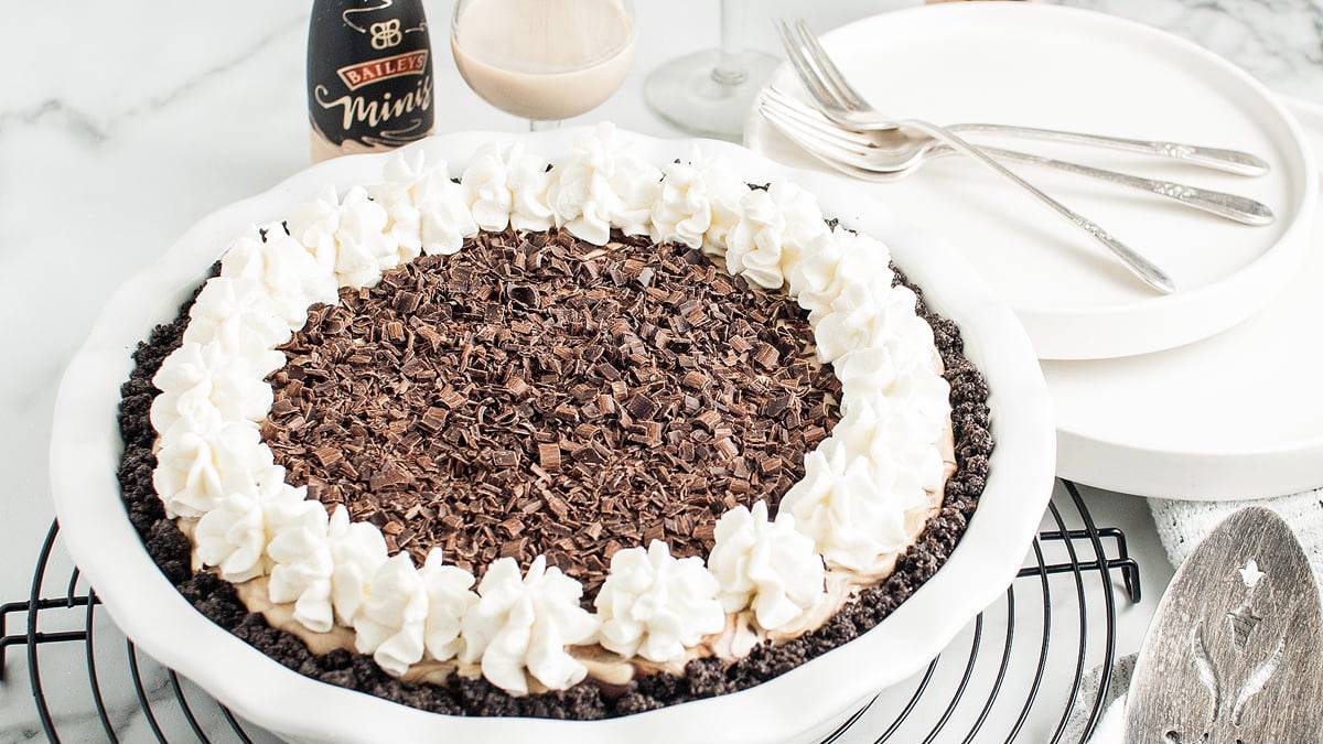 A sweet pie topped with chocolate and a bottle of baileys Irish cream.