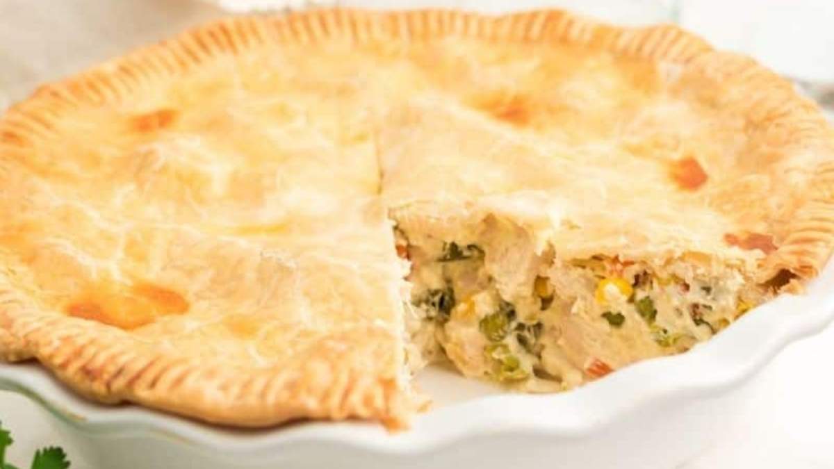 Chicken pot pie in a white dish with a slice taken out.