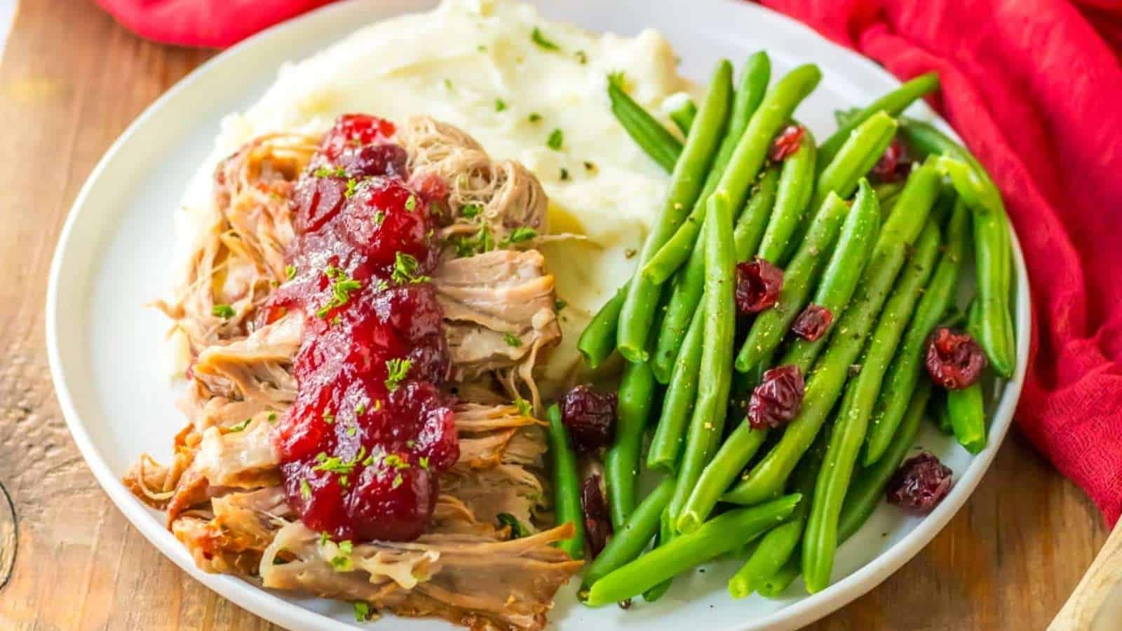 Pulled pork with cranberry sauce and green beans on a plate.