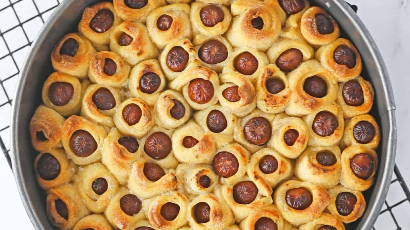 Sausage rolls in a pan on a cooling rack.