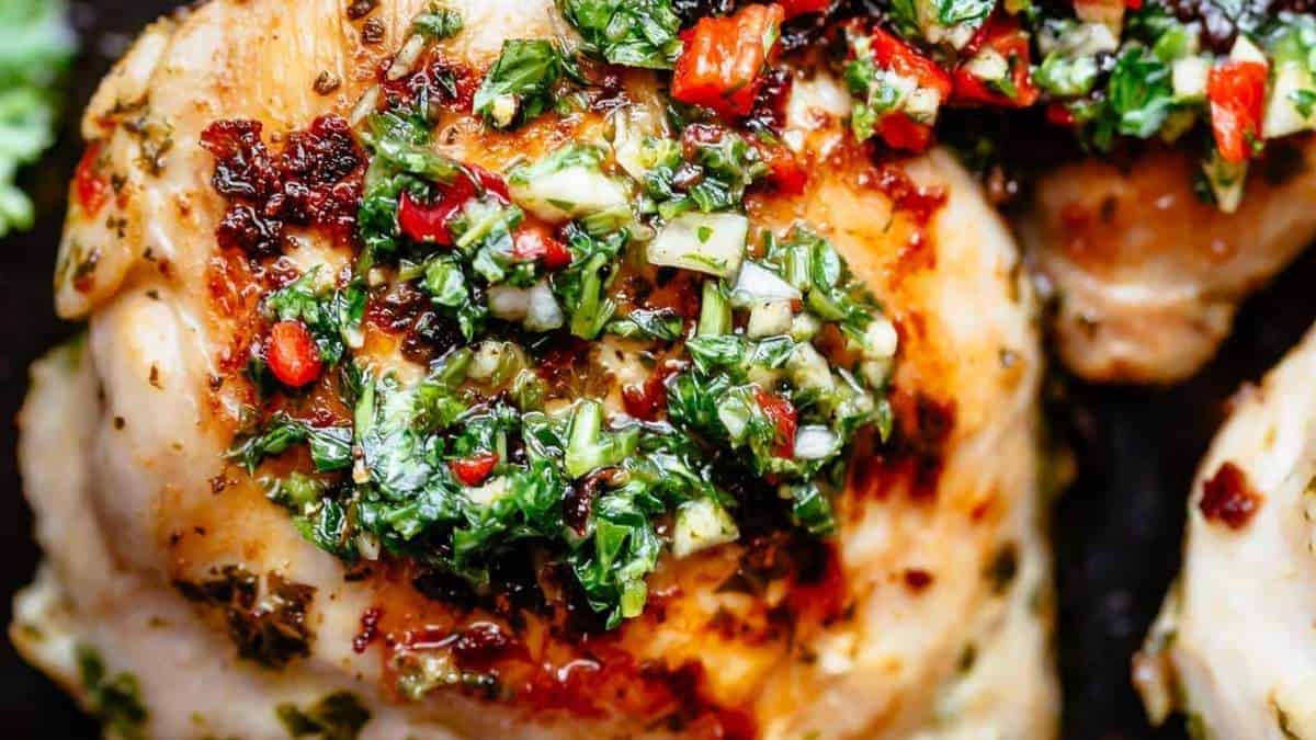 Chicken breasts with herbs and spices on a pan.