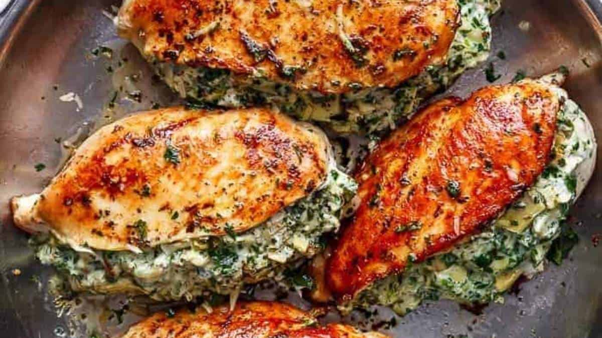 Chicken breasts topped with spinach and cheese in a skillet.