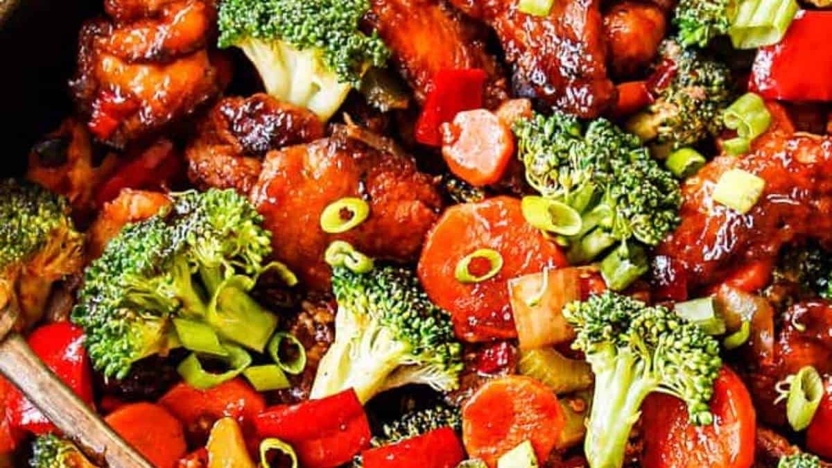 Chinese chicken stir fry in a skillet with broccoli and carrots.