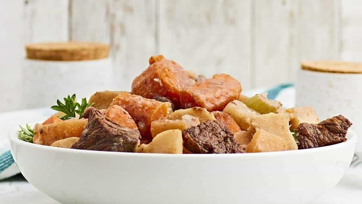 Beef stew in a white bowl on a table, perfect for soup recipes.