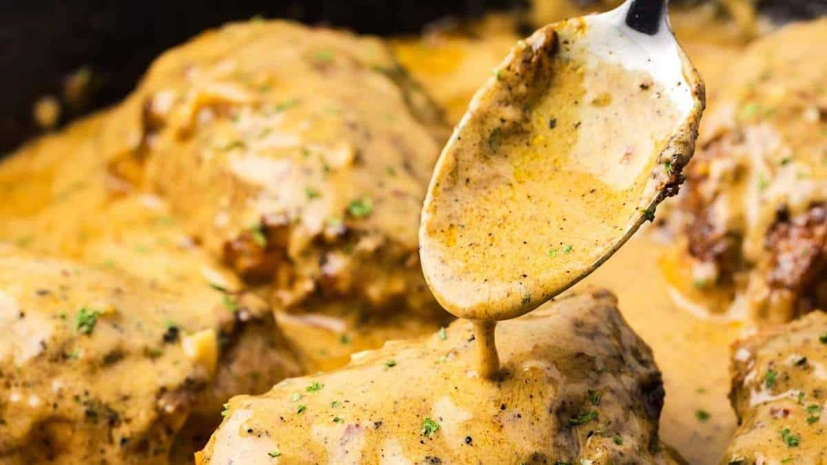 A shared recipe for comfort food where a spoon is used to drizzle sauce over chicken in a skillet.